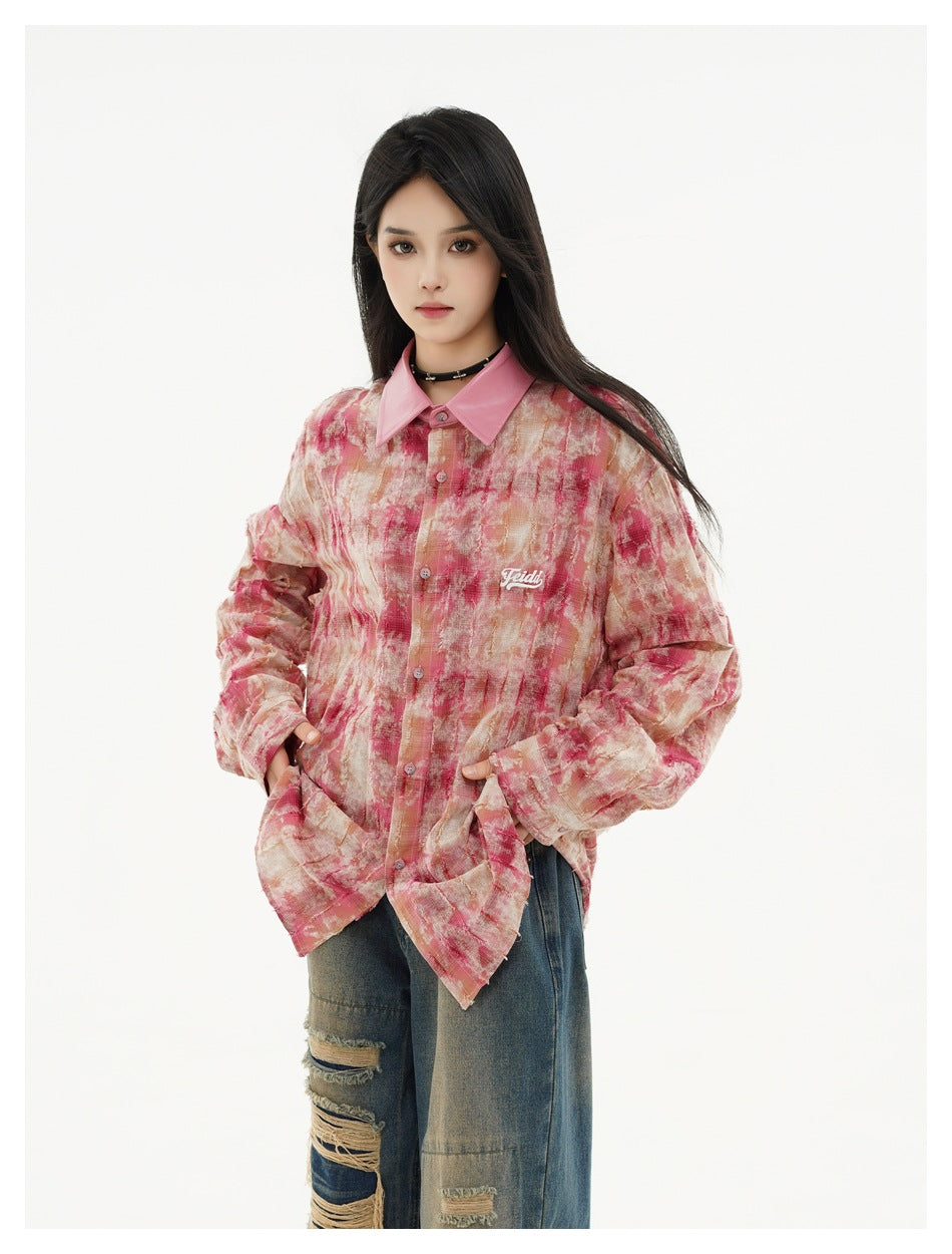 Model wearing an oversized pink and cream abstract-print button-up shirt with a pointed pink collar and distressed jeans.