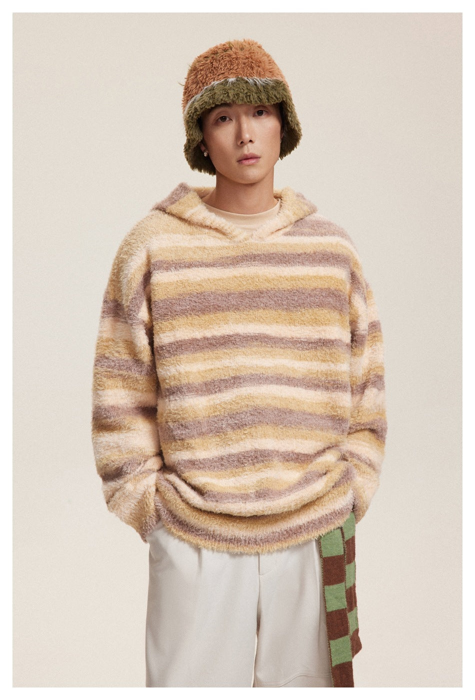 Front view of a model wearing a cream, tan, and mauve striped fuzzy hooded pullover.