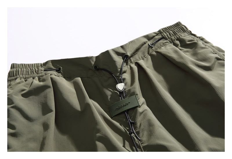 Close-up of olive shorts' elastic waistband, black drawcord and cord lock.