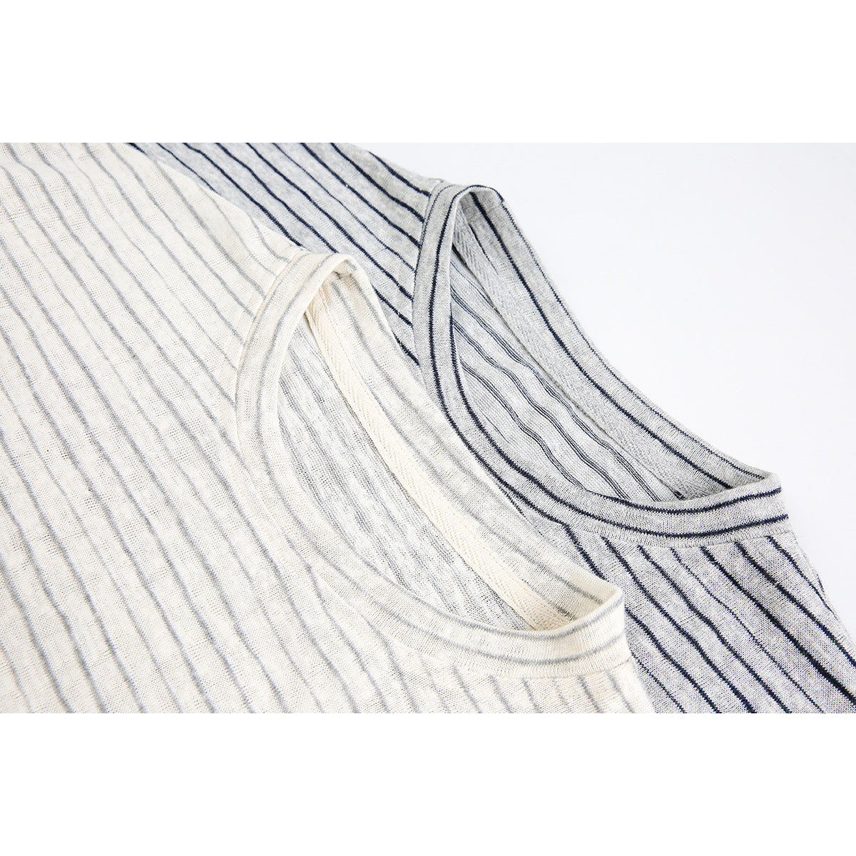 Close-up of two light-colored striped shirts showing their crew necklines and fine fabric texture.