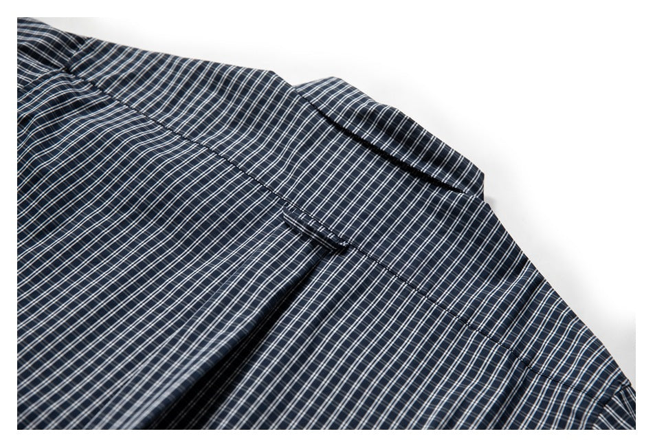 Close-up of navy plaid shirt fabric and seams, showing part of the collar and upper shirt.