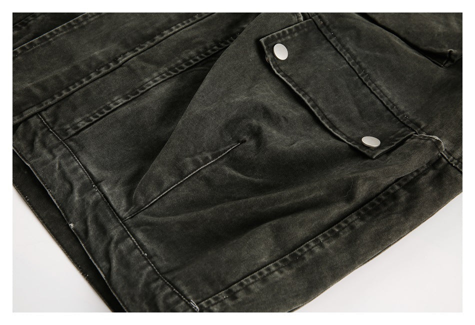 Close-up of the dark washed jacket's lower front, showing a snap-flap pocket and stitched hem.