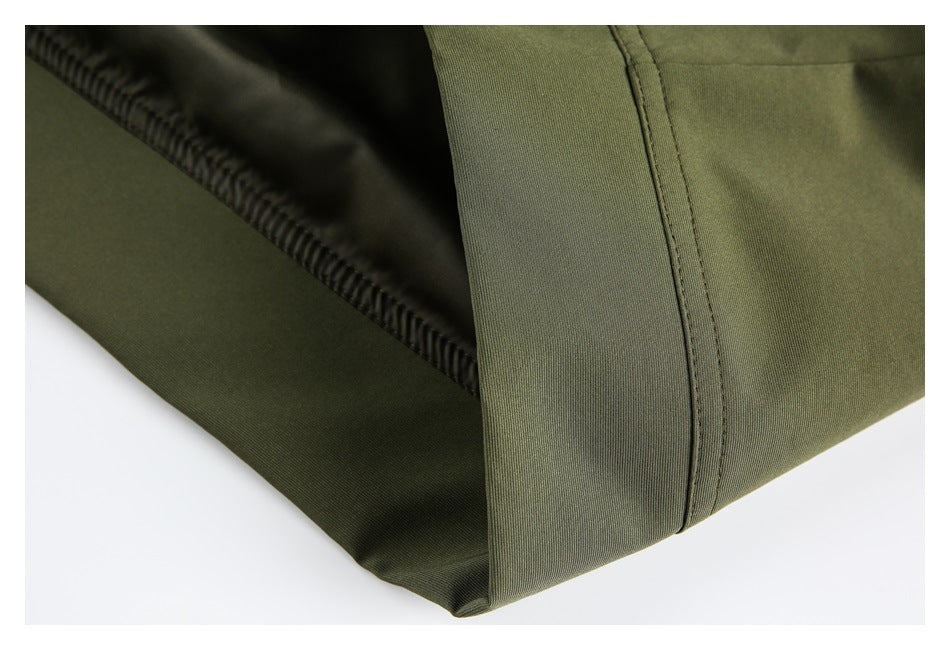 Close-up of an olive garment edge with visible dark overlock stitching and a curved seam.