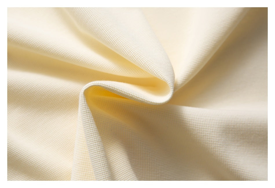 Close-up of softly folded ivory fabric showing a fine, subtle woven texture.