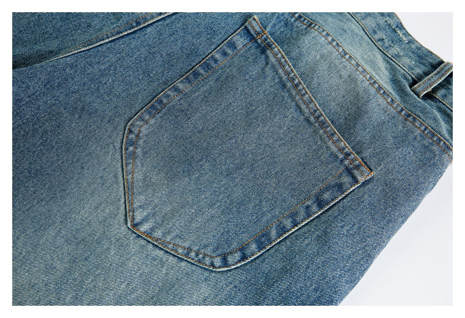 Close-up of a patch pocket on blue washed jeans with orange stitching.