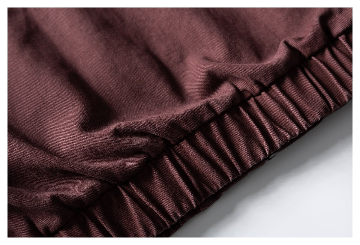 Close-up of a gathered seam and burgundy fabric with fine diagonal texture.