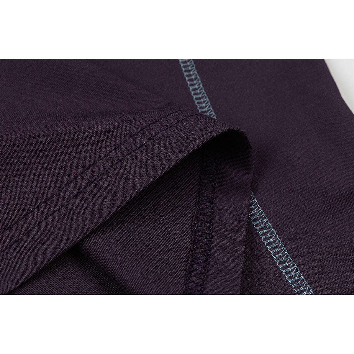 Close-up of the plum shirt’s stitched hem and contrast overlock seam.