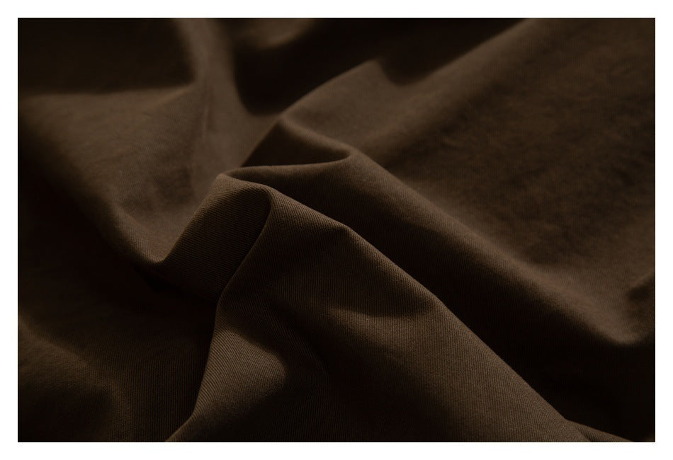 Close-up of dark brown fabric draped into folds, showing its surface texture.