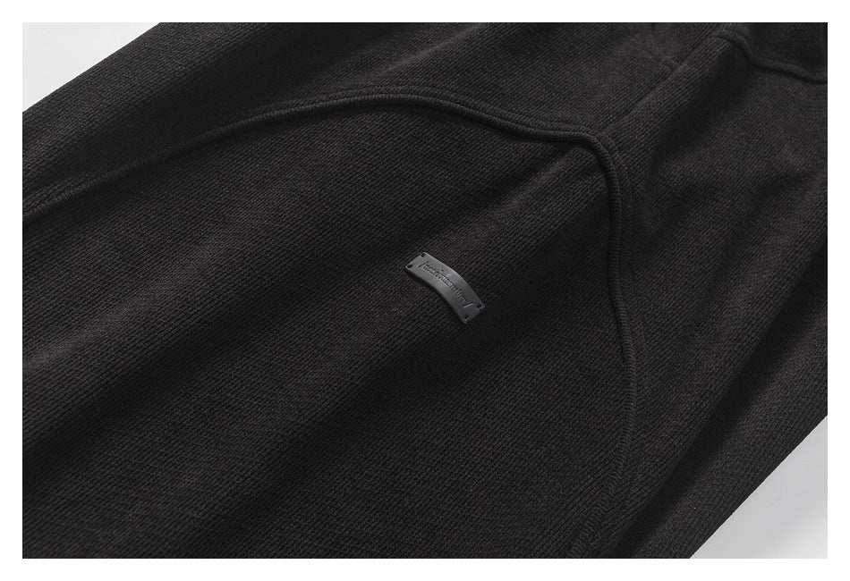 Close-up of black jogger fabric with a curved seam and small sewn label.