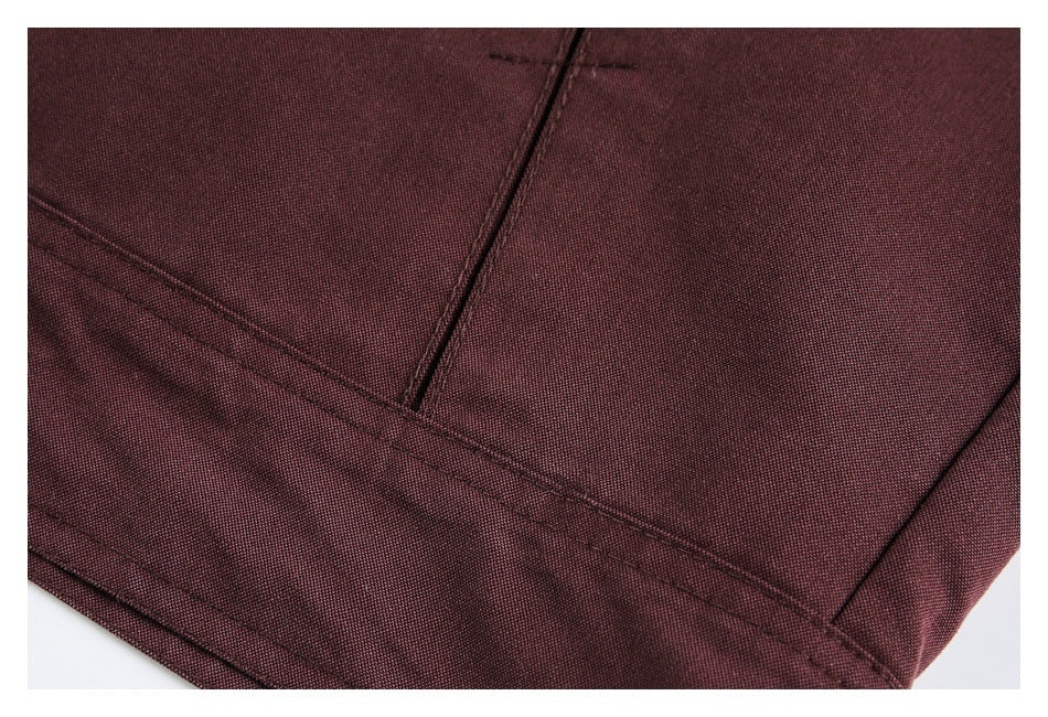 Close-up of burgundy fabric with intersecting stitched seams and a folded hem.