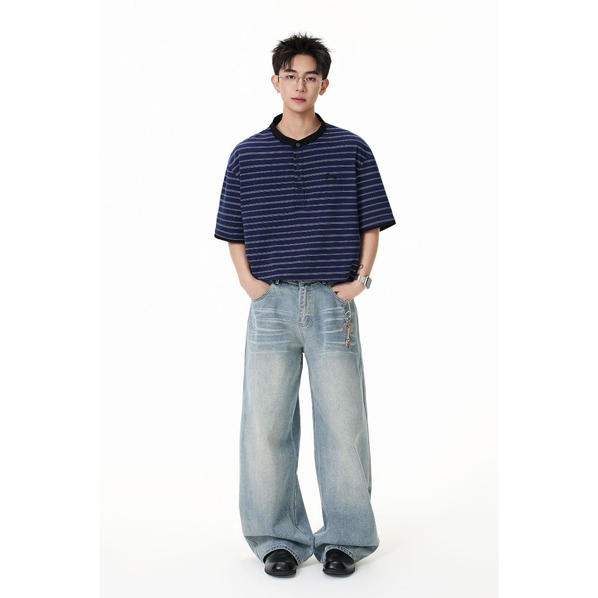 Model wearing a navy striped short-sleeve henley with black trim and wide-leg light-wash jeans.