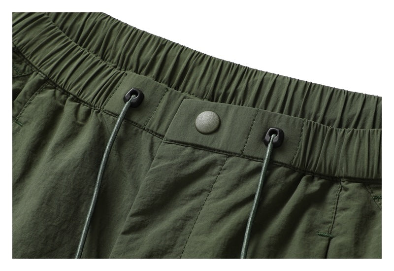 Close-up of the dark olive shorts' elastic waistband, snap closure and drawcord eyelets.