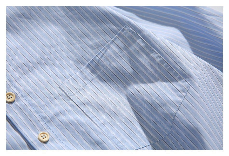 Close-up of a stitched chest pocket on the light blue pinstriped shirt.