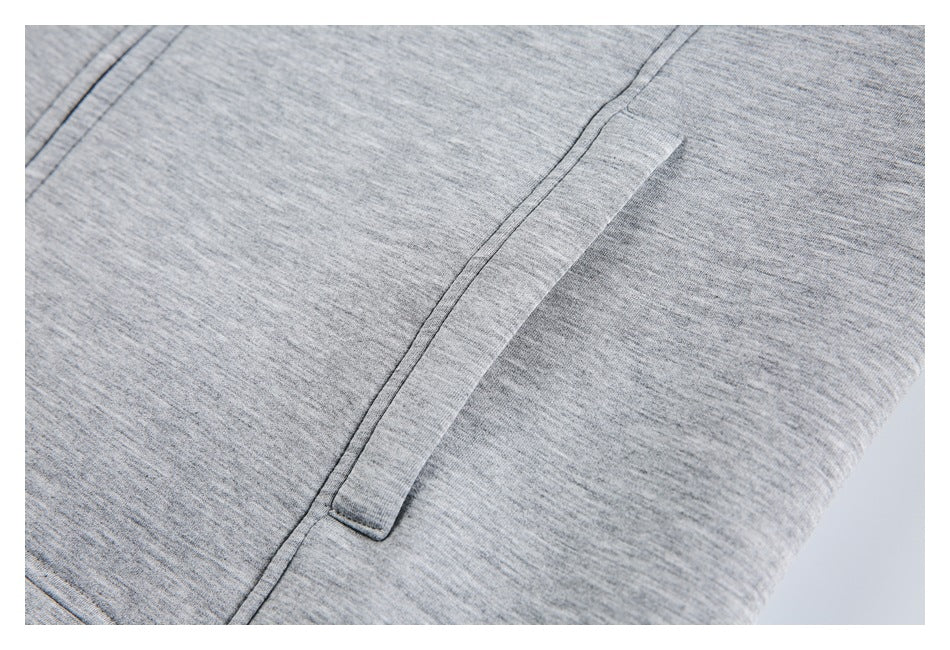Close-up of heather gray knit fabric with a narrow stitched fabric tab beside a seam.