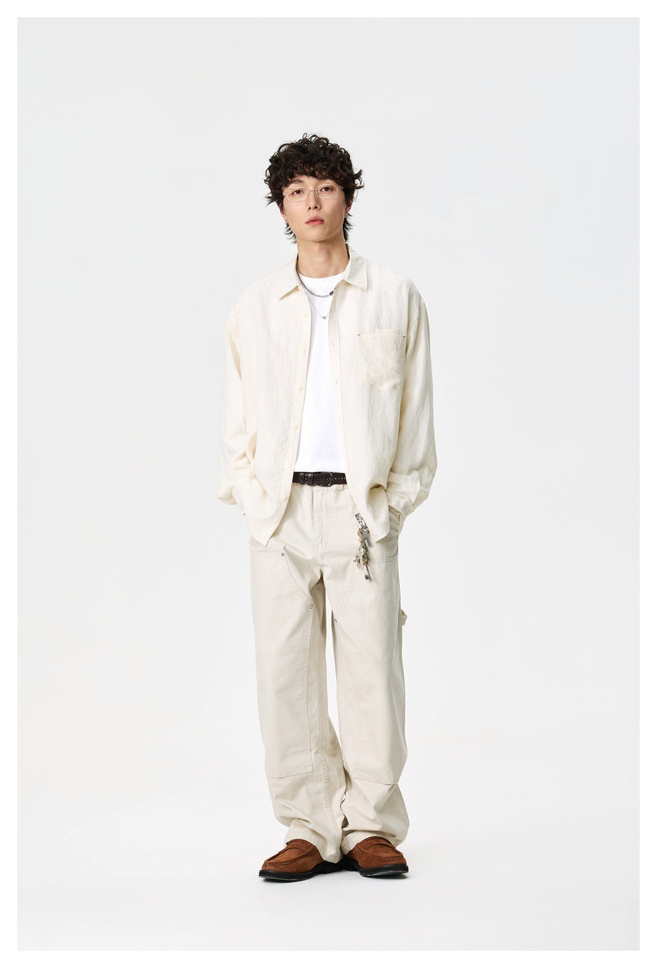 Full-length front view of a model wearing an ivory button-up shirt over a white T-shirt with matching trousers.