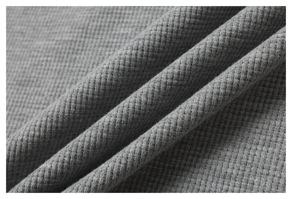 Macro view of gray waffle-knit fabric draped in soft folds.