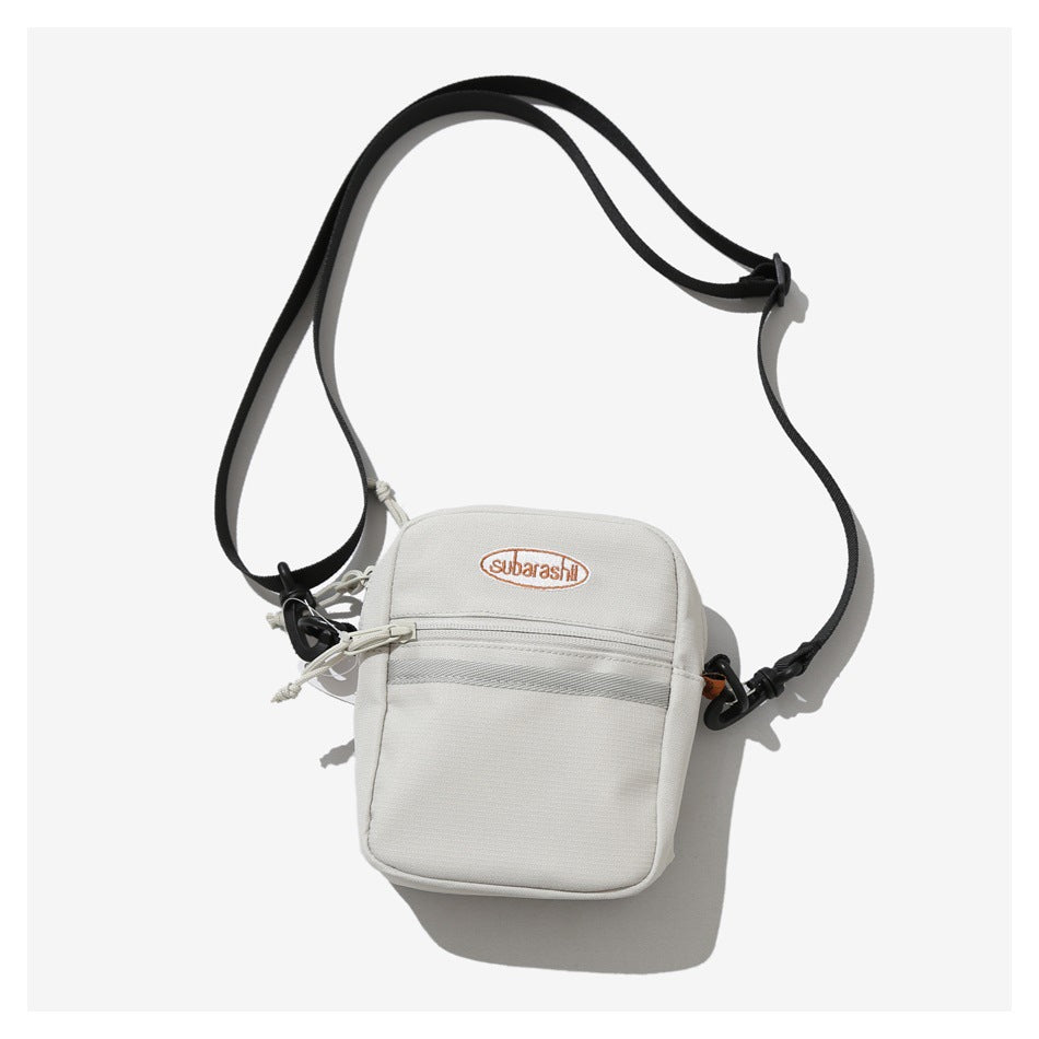 Front view of an off-white crossbody bag with a front zip pocket, embroidered logo, and black adjustable strap.