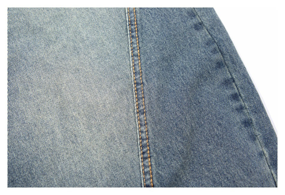 Close-up of blue denim showing a vertical seam with orange double stitching.