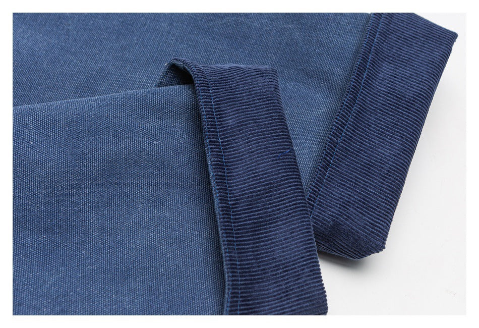 Close-up of blue jacket fabric and dark ribbed trim at the collar or cuff.