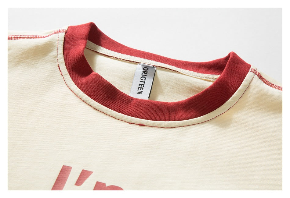 Close-up of an ivory T-shirt's red ribbed crew neck, stitched seams, and sewn-in neck label.