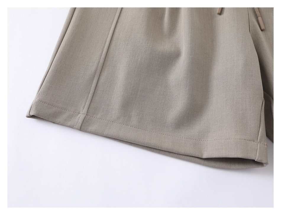 Close-up of taupe trouser leg showing the stitched hem and side seam.