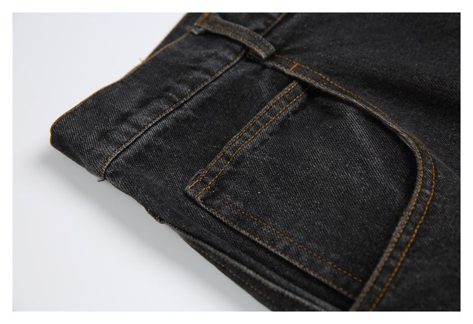 Close-up of black jeans showing a front pocket, belt loop, and contrast brown stitching.