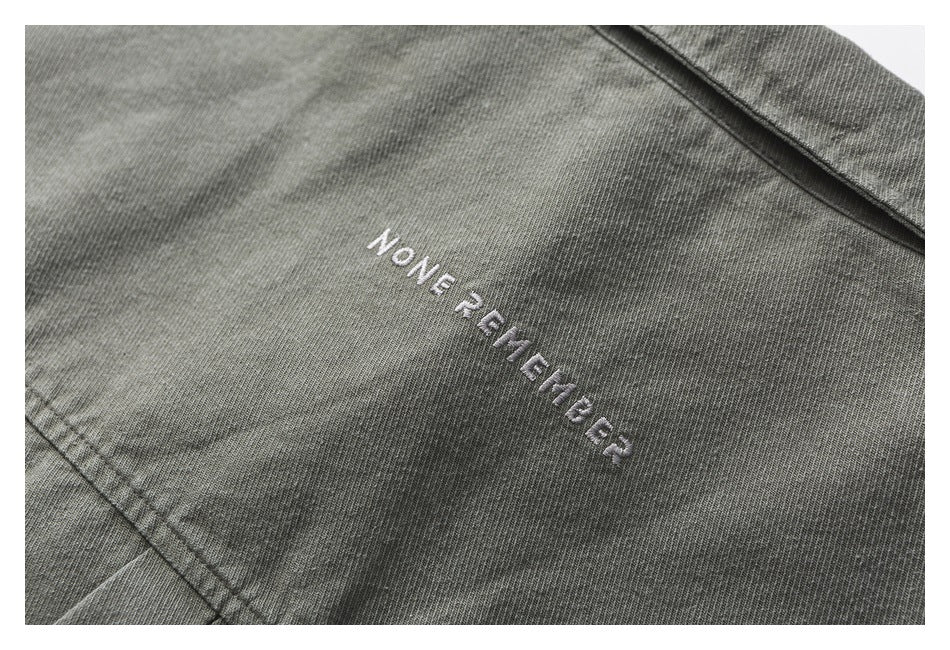 Close-up of a gray garment with white embroidered English lettering and visible seam stitching.