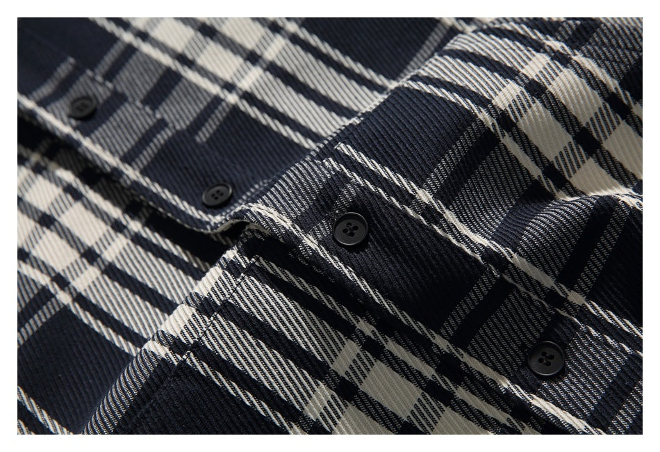 Close-up of black buttons and stitching on the black, cream, and gray plaid shirt.