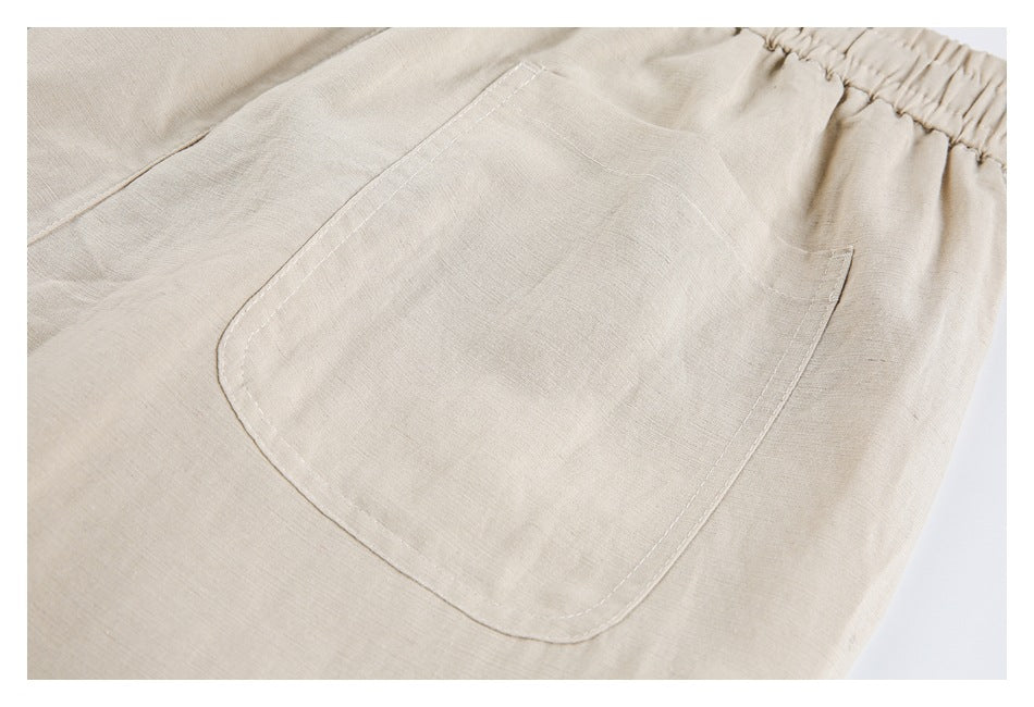 Back close-up of beige trousers showing a large patch pocket and gathered elastic waistband.