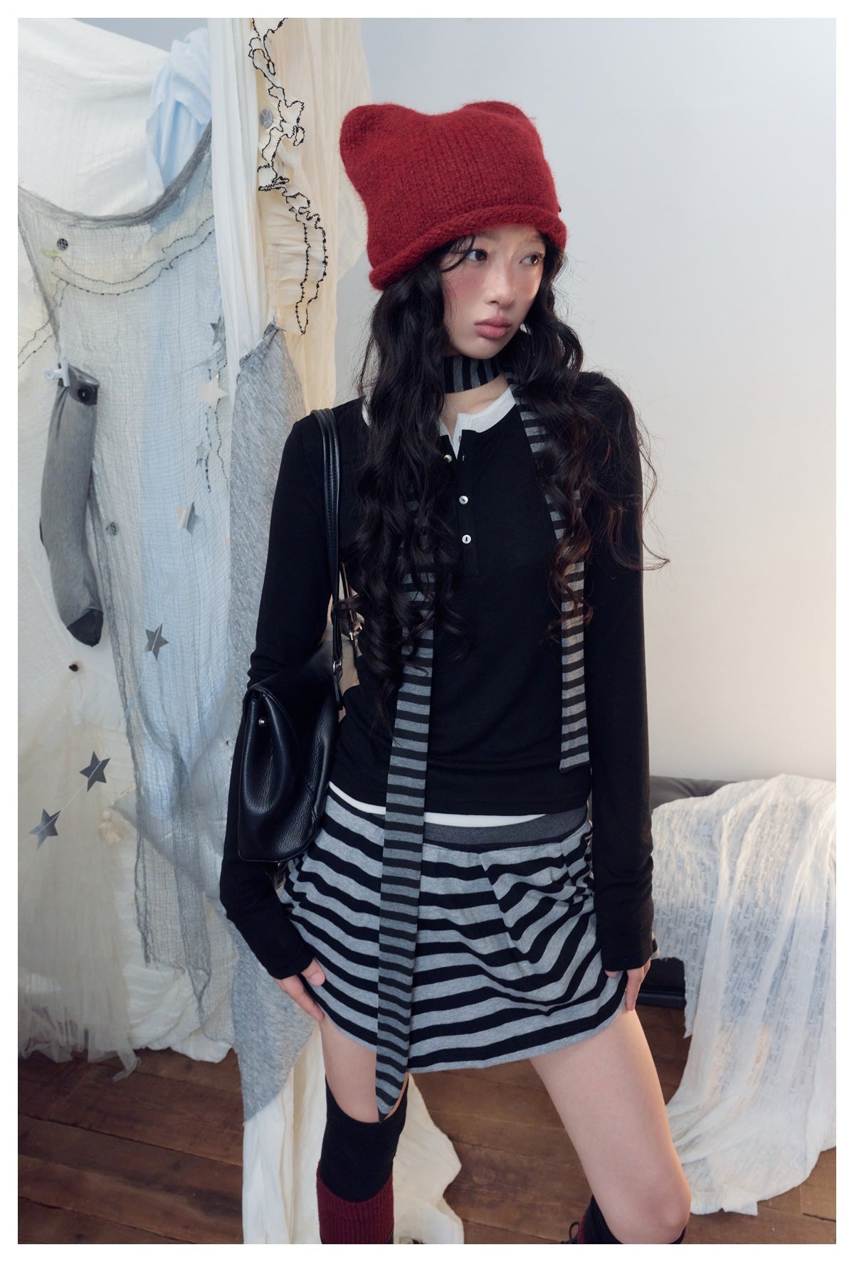 Model wearing a black button-front top and gray-and-black striped mini skirt with a matching long scarf.