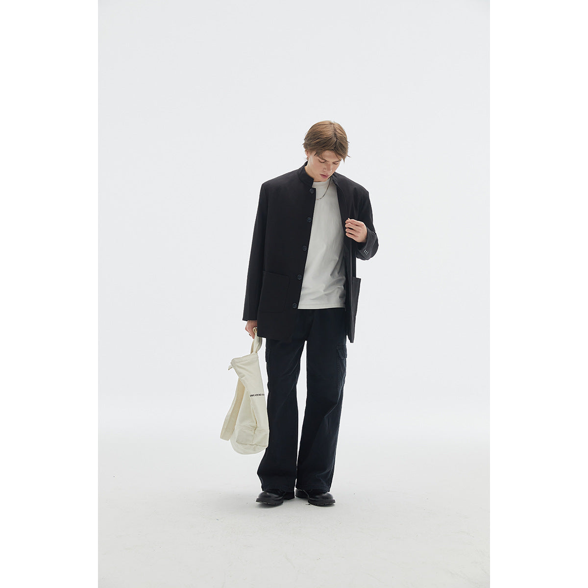 Full-length view of a model wearing a black stand-collar button-front jacket, white T-shirt and black cargo trousers.