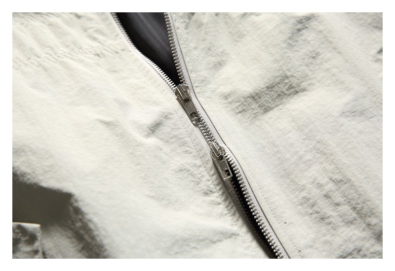 Close-up of a silver zipper on pale gray crinkled fabric, with dark lining visible beneath.