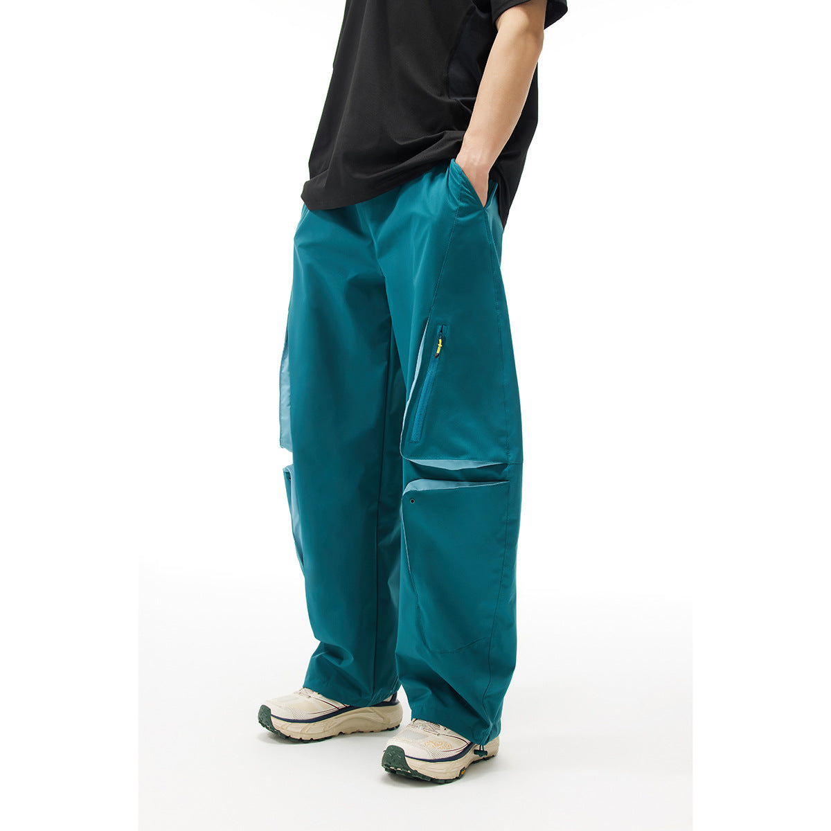 Model wearing teal wide-leg cargo pants with large flap pockets and zip pockets, shown from the front.