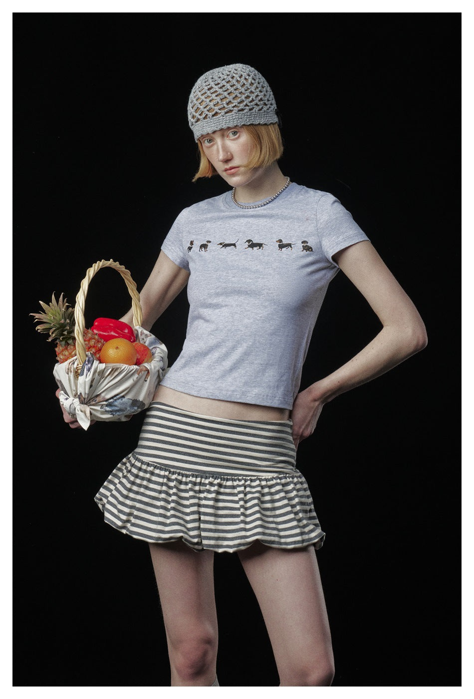 Model wearing a pale gray T-shirt with small dog prints and a gray-and-white striped ruffle skirt.