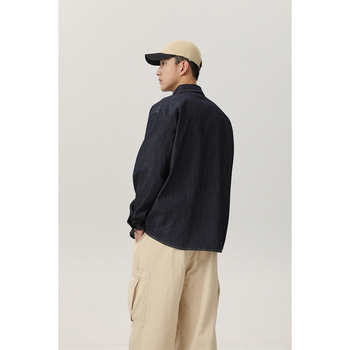 Rear three-quarter view of a model wearing a dark indigo shirt and beige cargo pants.