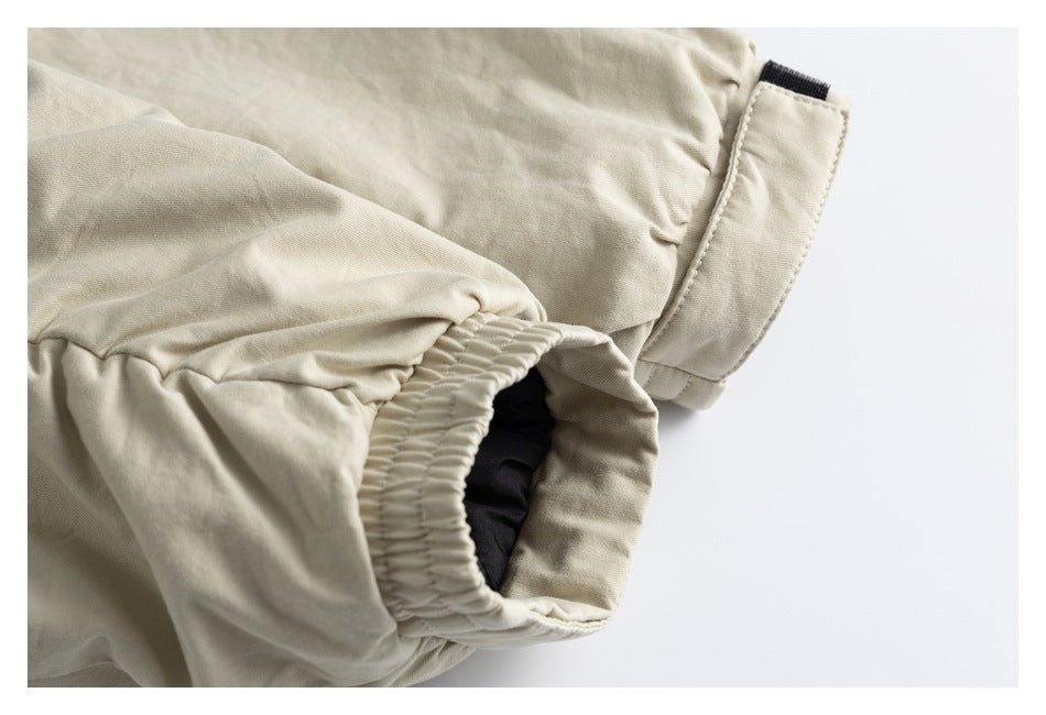 Close-up of a beige garment cuff with gathered elastic and a hook-and-loop fastening tab.