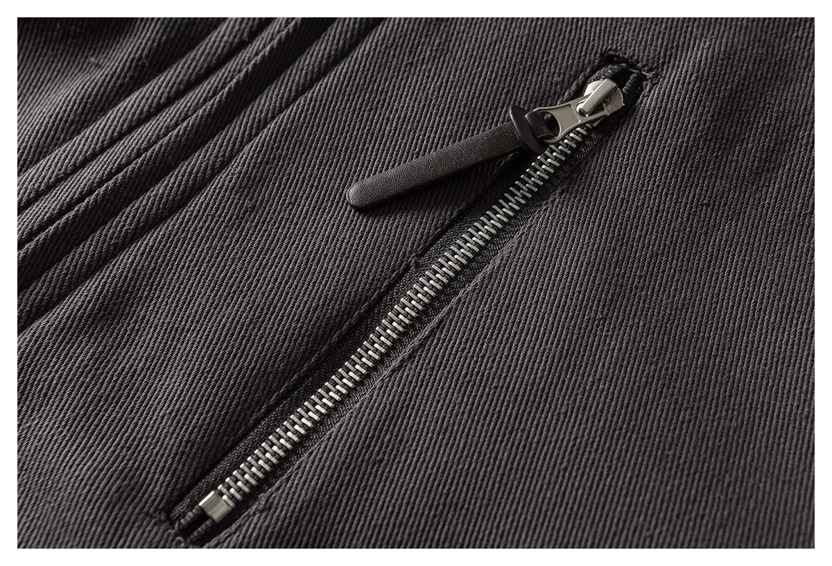 Close-up of a silver zipper with a dark pull on charcoal gray ribbed fabric.