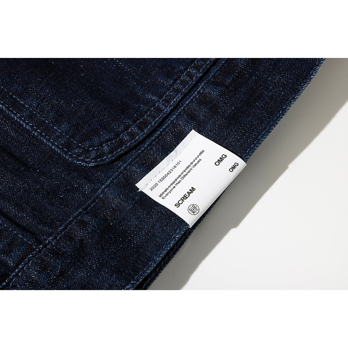Close-up of a white sewn label with black lettering on dark indigo denim.