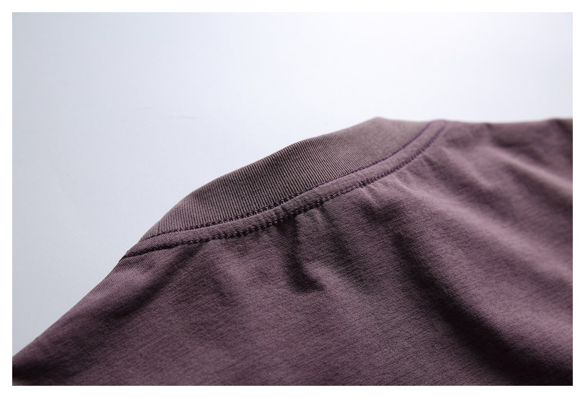 Close-up of a muted plum T-shirt showing its ribbed crew neckline and stitching.