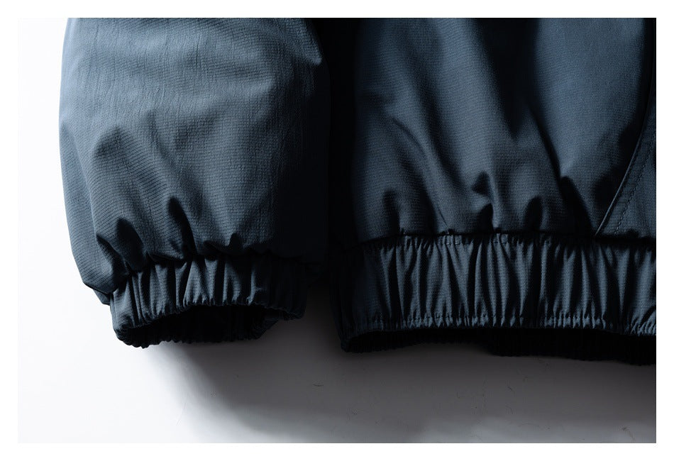 Close-up of a dark jacket sleeve and lower edge, both finished with gathered elastic cuffs.