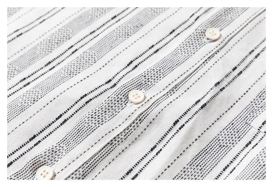 Close-up of the cream shirt's black stripe pattern and placket with three white buttons.