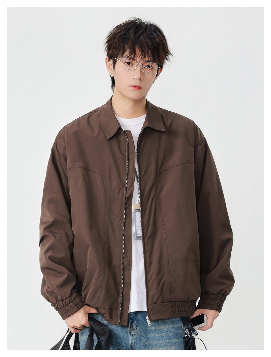 Model wearing a brown zip-front jacket with a pointed collar, elastic cuffs and hem, over a white shirt.