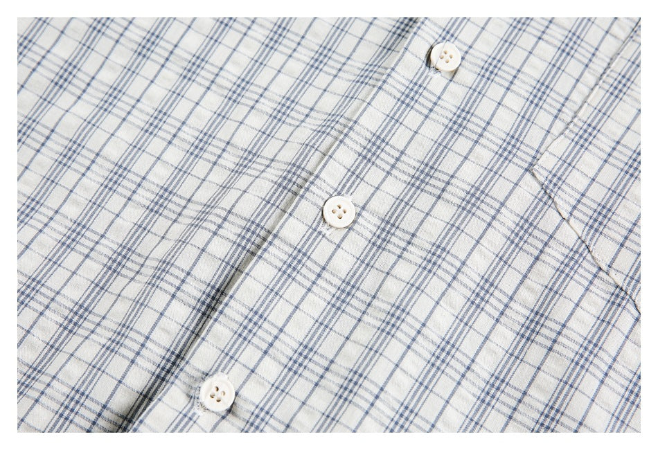 Close-up of the white buttons and front placket on a blue-gray plaid shirt.