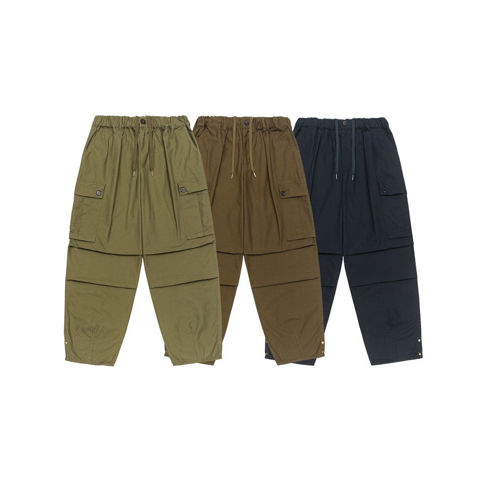 Front views of cargo pants in olive, brown and navy, with elastic waists, drawstrings and large side pockets.