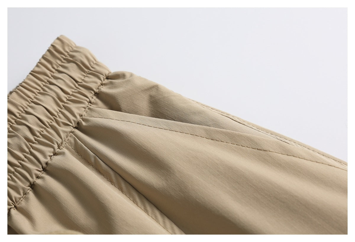 Close-up of a gathered elastic waistband and stitched panels on a tan garment.