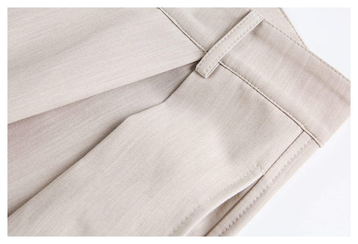 Close-up of beige trousers showing a belt loop, waistband, and stitched pocket seam.
