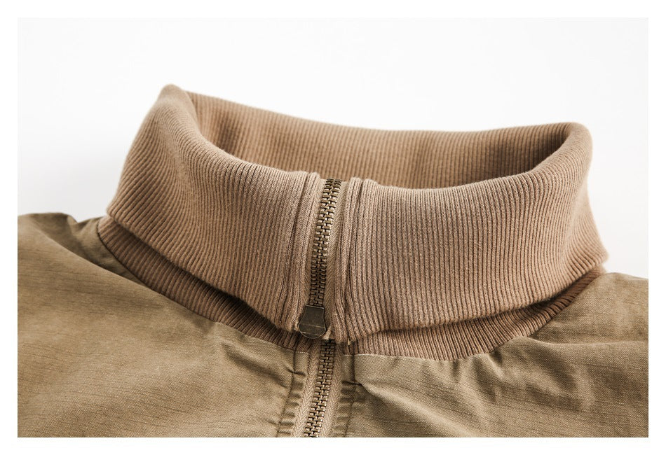 Close-up of a tan jacket’s ribbed stand collar and front zipper.