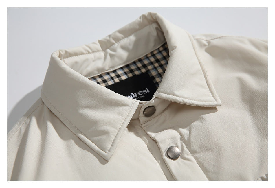 Close-up of an ivory jacket’s pointed collar and snap placket, with checked lining visible inside.