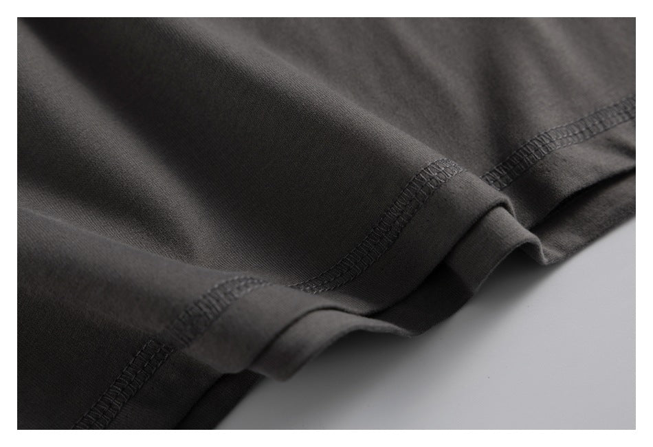 Close-up of overlapping dark charcoal fabric folds and stitched hem edges.
