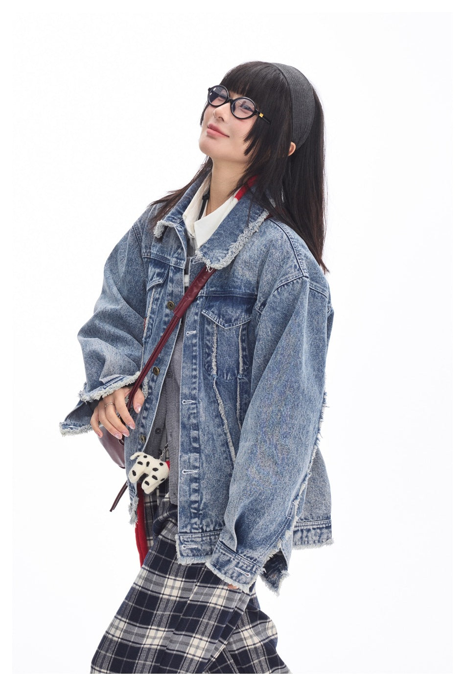 Close view of a model wearing an oversized faded blue denim jacket with frayed trim and flap pockets.